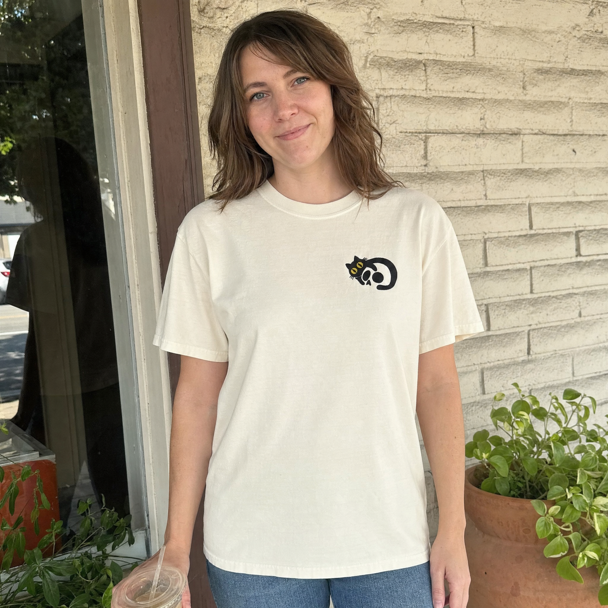 Model wearing the Black Cat Skull comfort colors tee in Ivory, lifestyle image 1