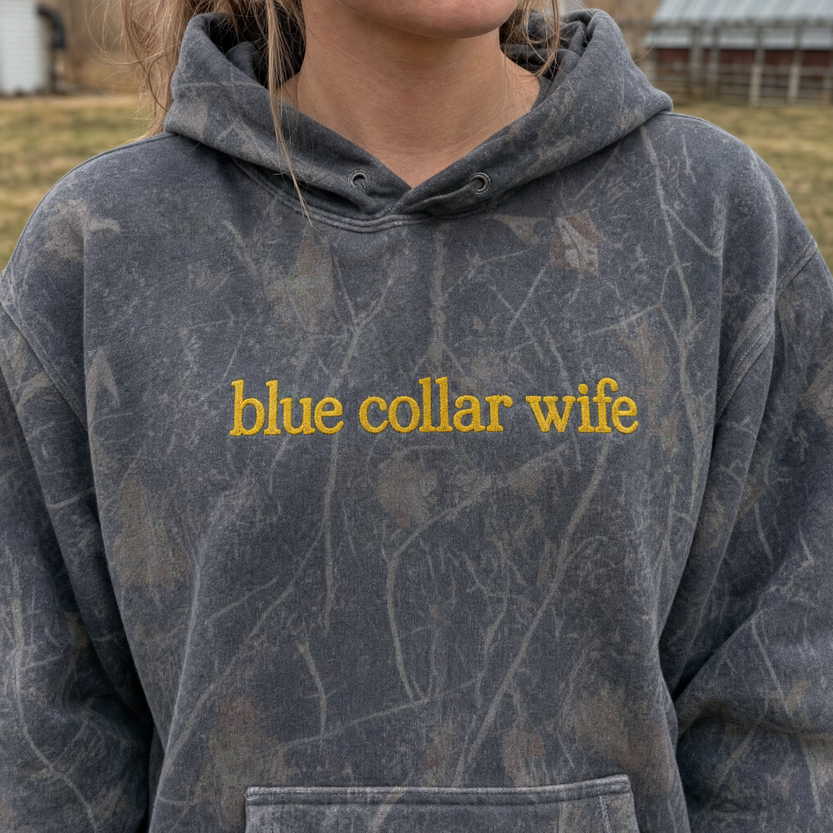 Model wearing the Blue Collar Wife heavyweight hoodie in Dark Tree Camo, lifestyle image 1