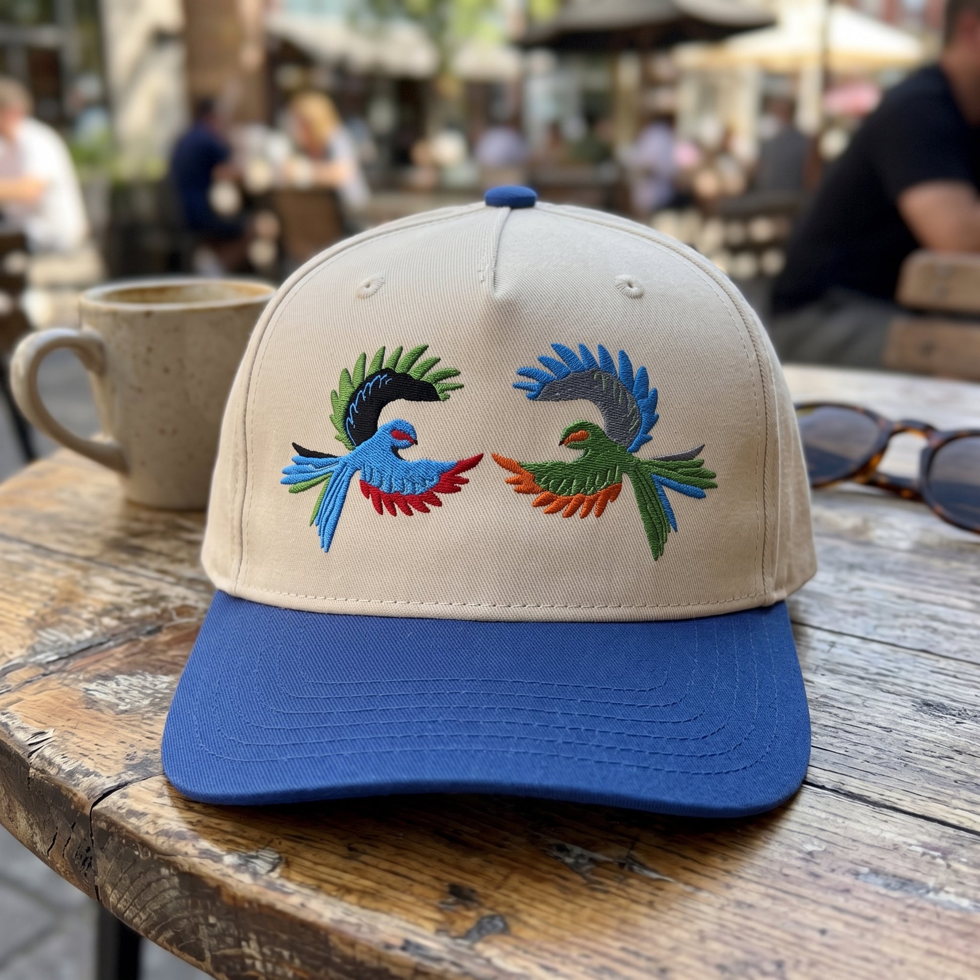 Colorful Tropical Bird embroidered hat in Royal/natural resting on a flat surface