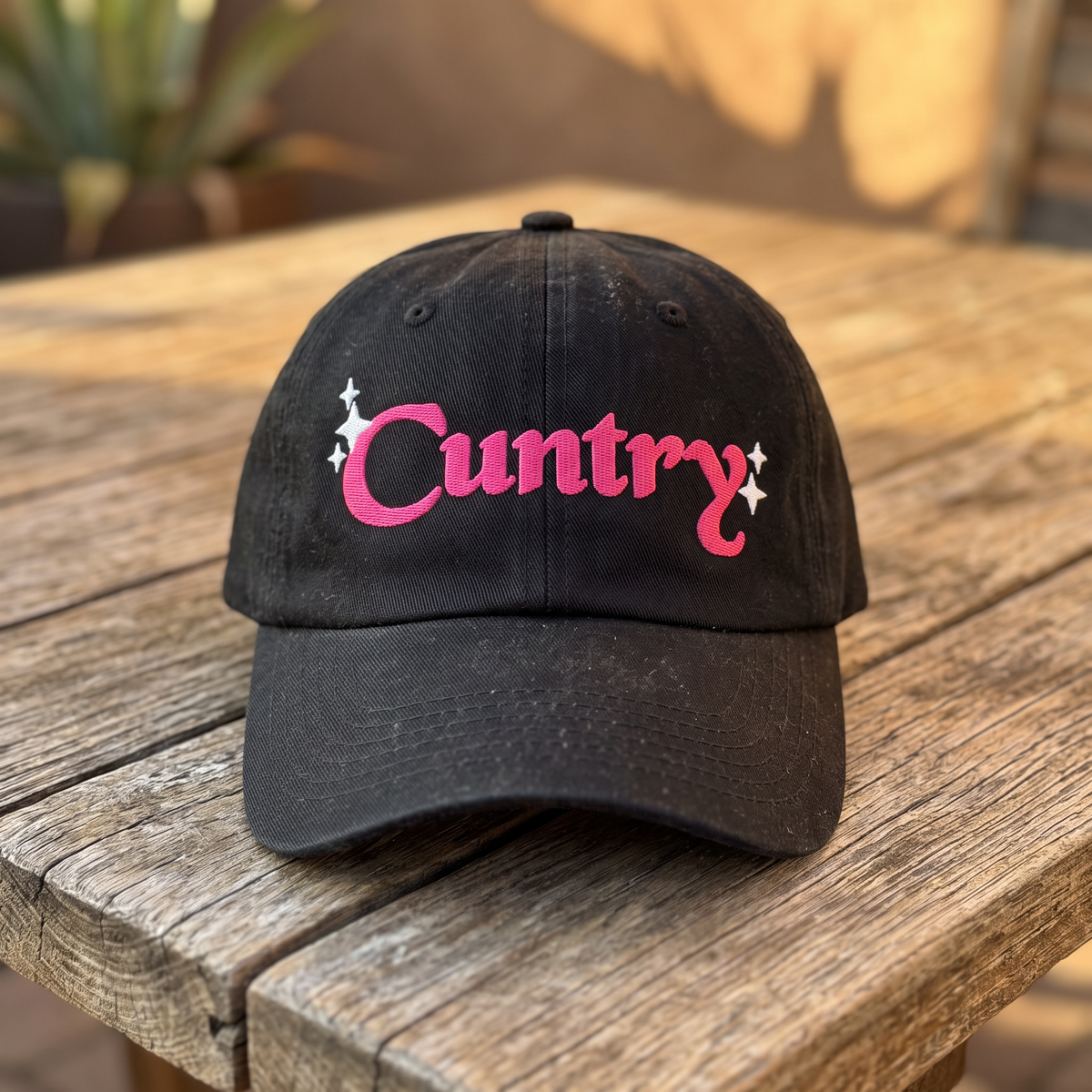 Country Word Art embroidered hat in Black resting on a flat surface, lifestyle image 2