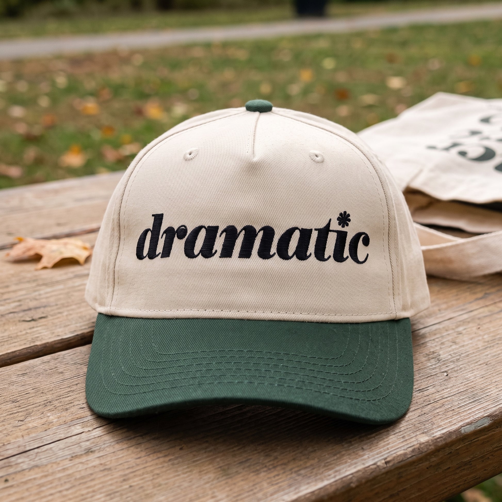 Dramatic Text embroidered hat in Dark Green/natural resting on a flat surface
