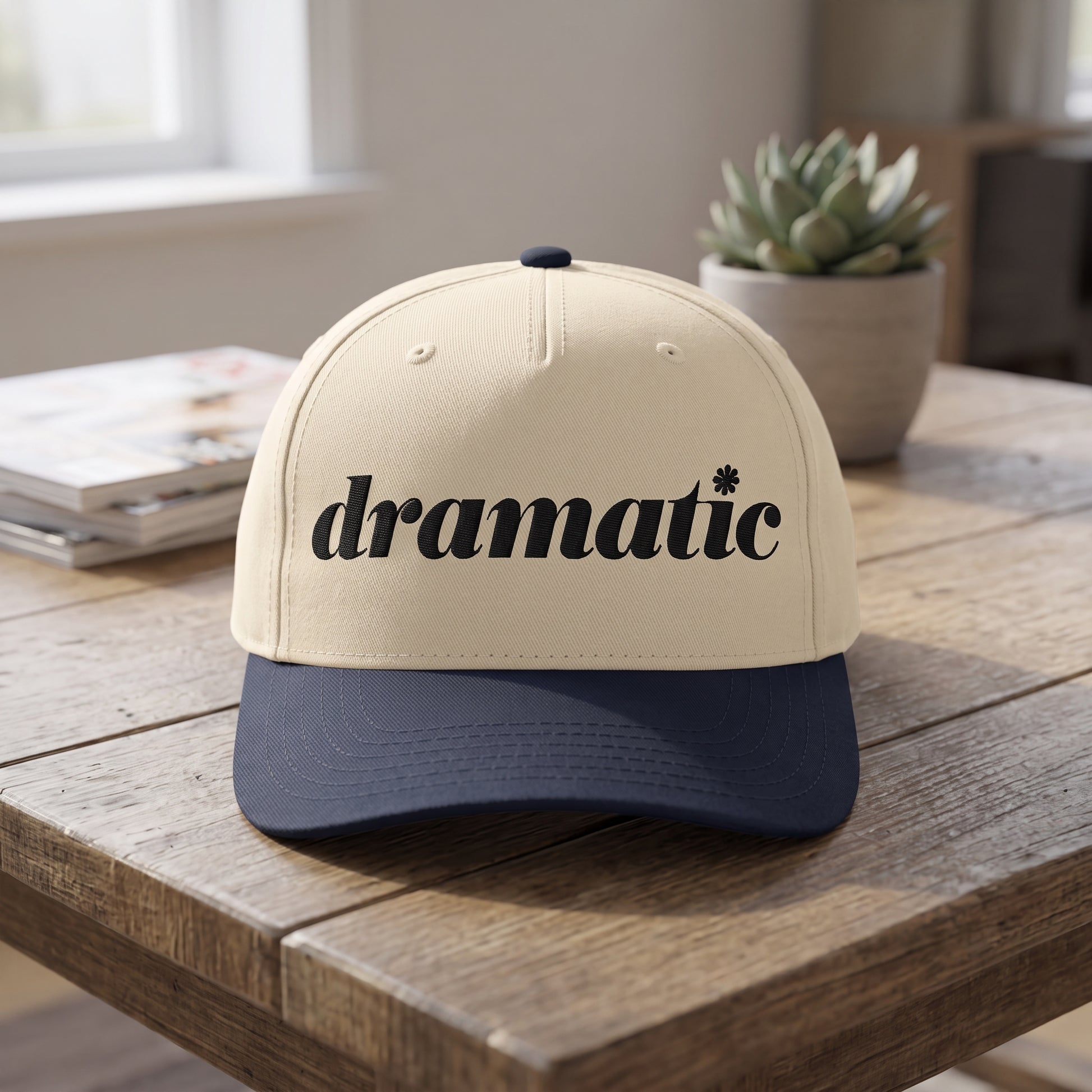 Dramatic Text embroidered hat in Navy/natural resting on a flat surface