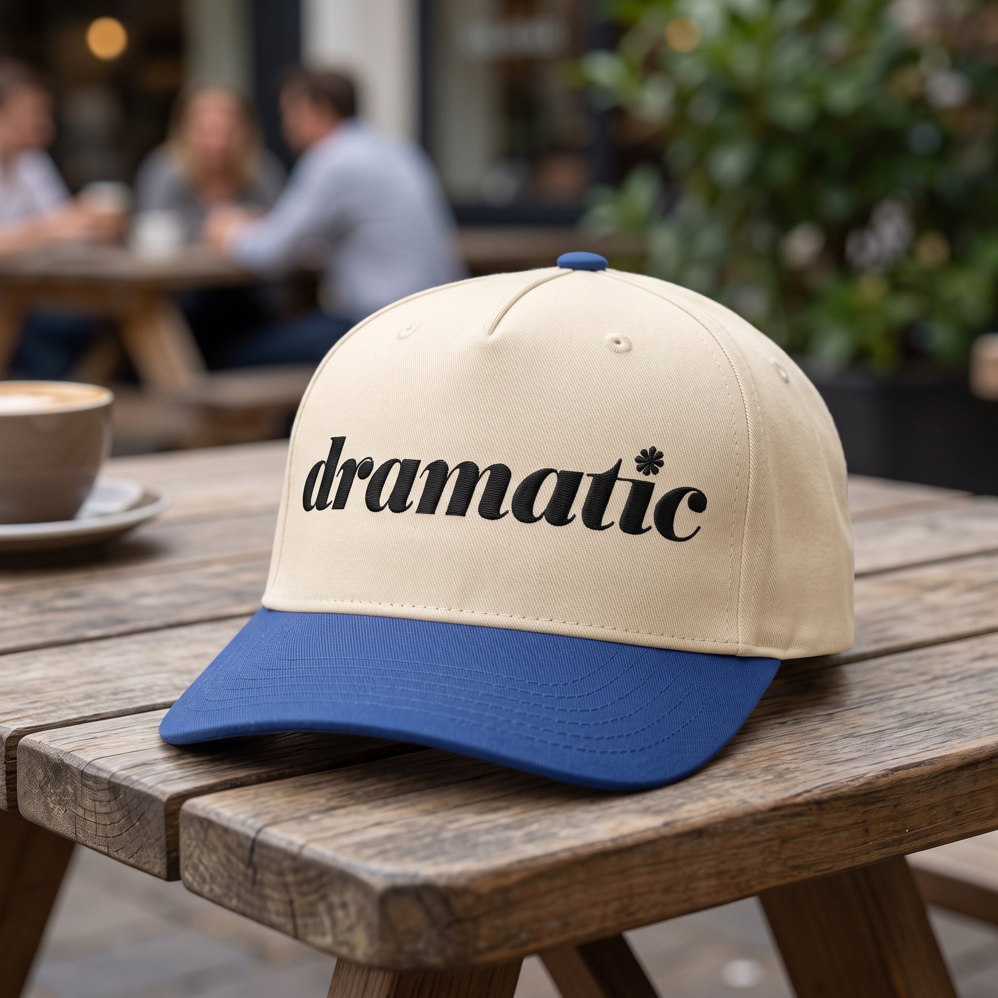 Dramatic Text embroidered hat in Royal/natural resting on a flat surface