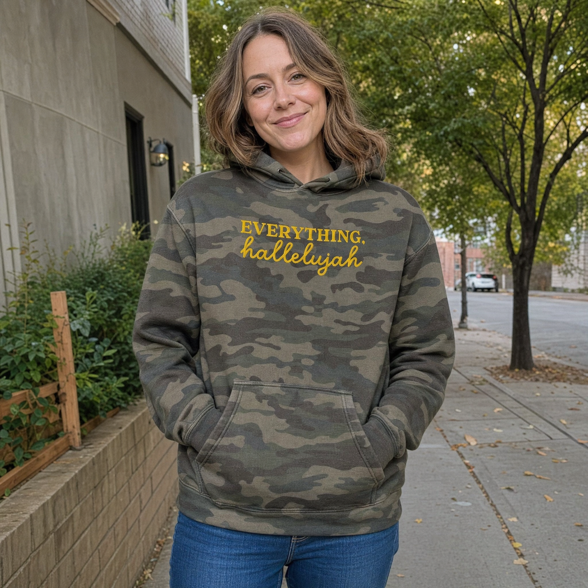 Model wearing the Everything Hallelujah heavyweight hoodie in Green Camo, lifestyle image 1