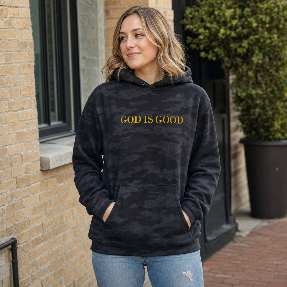 Model wearing the God Is Good heavyweight hoodie in Black Camo, cover image 1
