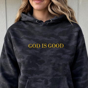 Model wearing the God Is Good heavyweight hoodie in Black Camo, lifestyle image 1