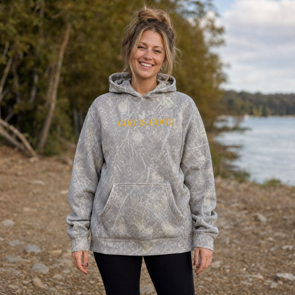 Model wearing the God Is Good heavyweight hoodie in Deadwood Tree Camo, lifestyle image 1