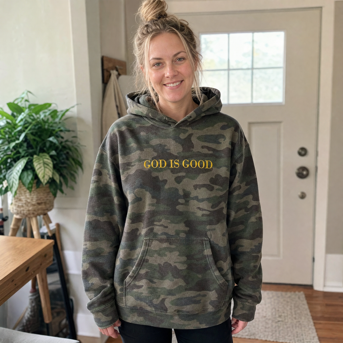 Model wearing the God Is Good heavyweight hoodie in Forest Camo, lifestyle image 1