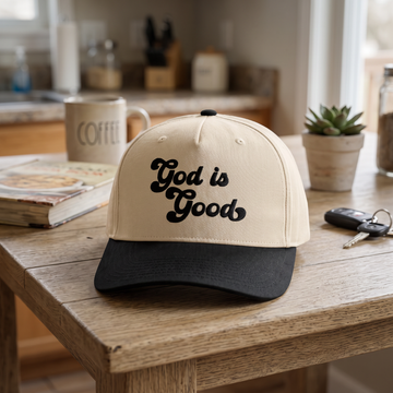 God is Good embroidered hat in Black/natural resting on a flat surface