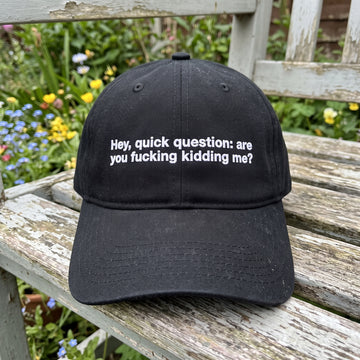 Hey Quick Question embroidered hat in Black resting on a flat surface, lifestyle image 1