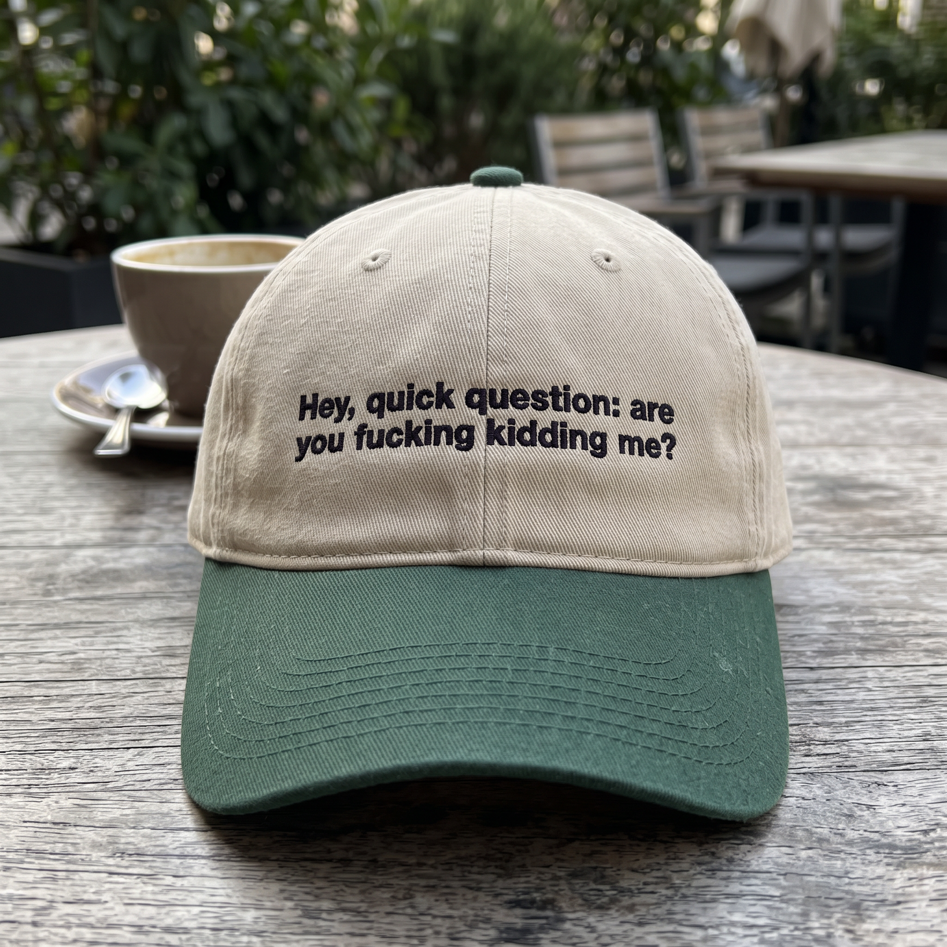 Hey Quick Question embroidered hat in Dark Green/khaki resting on a flat surface, lifestyle image 2