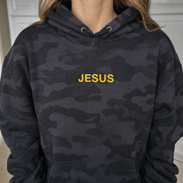 Model wearing the JESUS Text heavyweight hoodie in Black Camo, lifestyle image 1