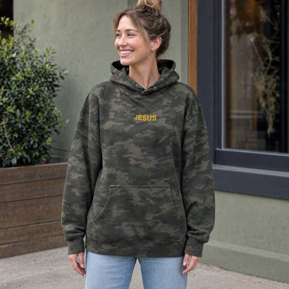 Model wearing the JESUS Text heavyweight hoodie in Green Camo, lifestyle image 1