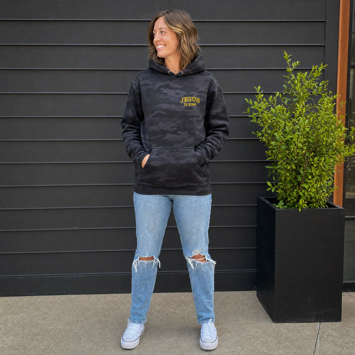 Model wearing the Jesus Is King heavyweight hoodie in Black Camo, cover image 1