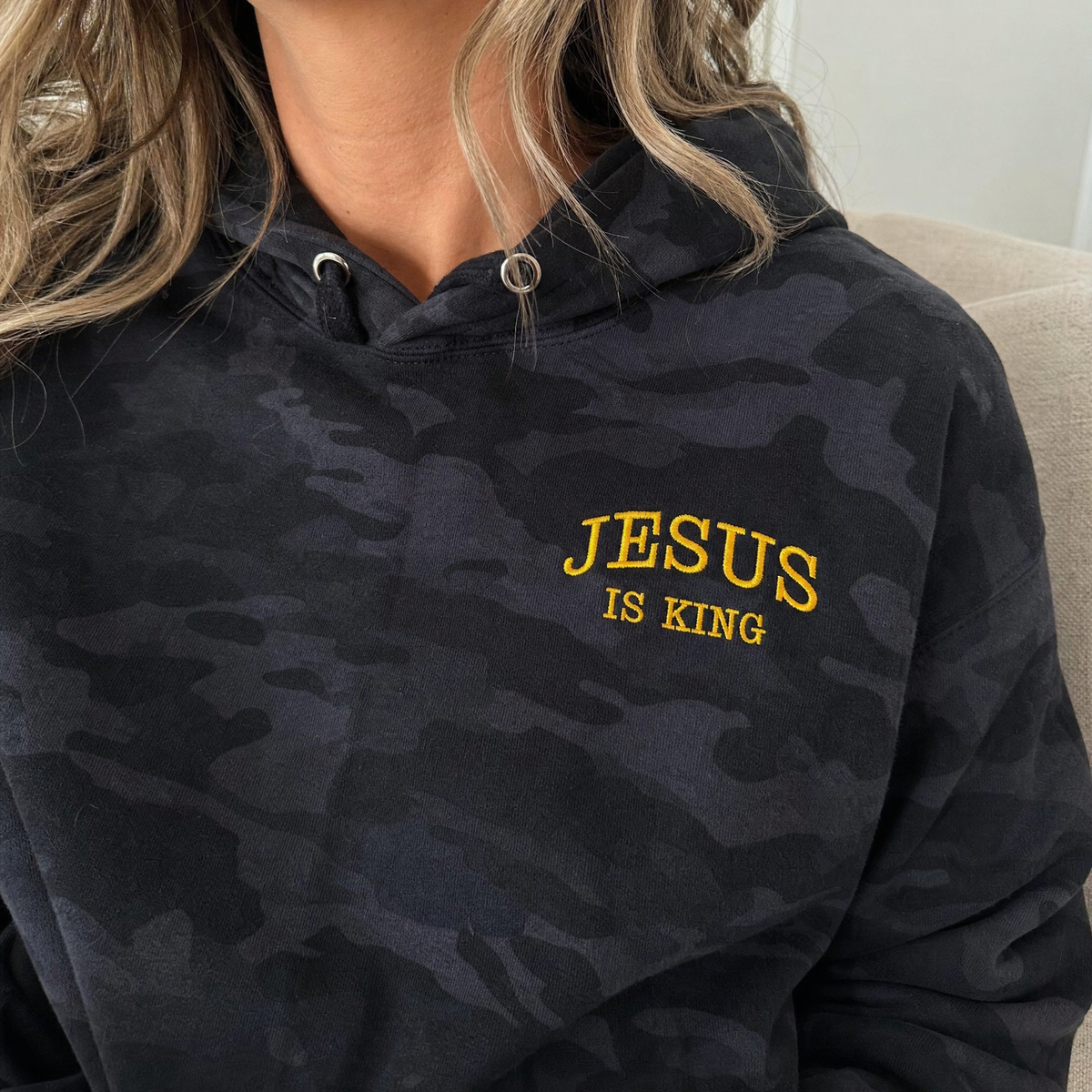 Model wearing the Jesus Is King heavyweight hoodie in Black Camo, lifestyle image 1