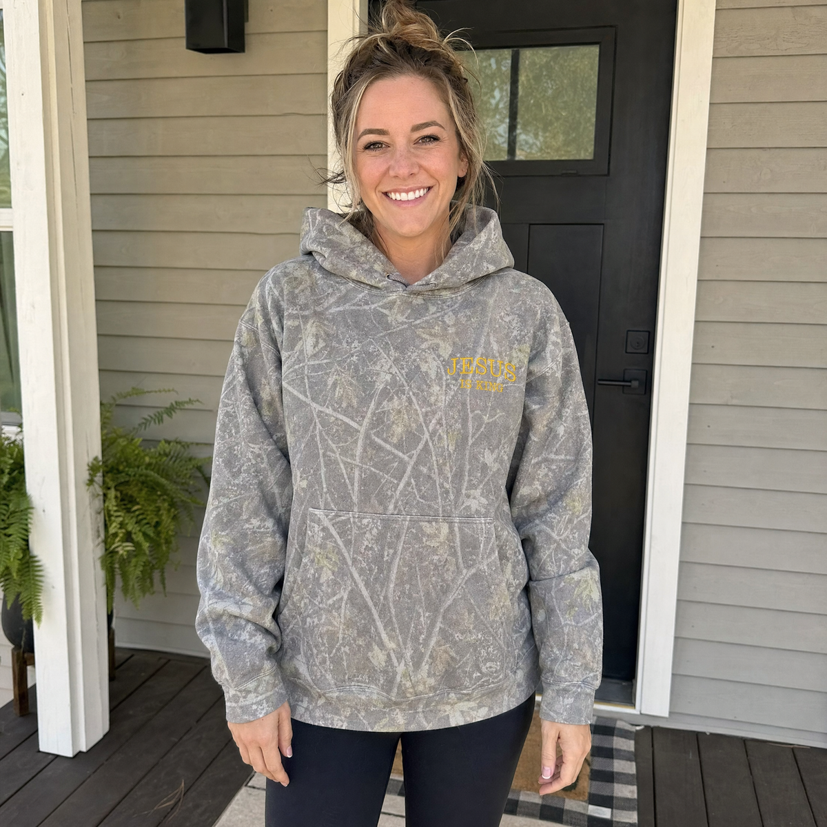 Model wearing the Jesus Is King heavyweight hoodie in Deadwood Tree Camo, lifestyle image 1