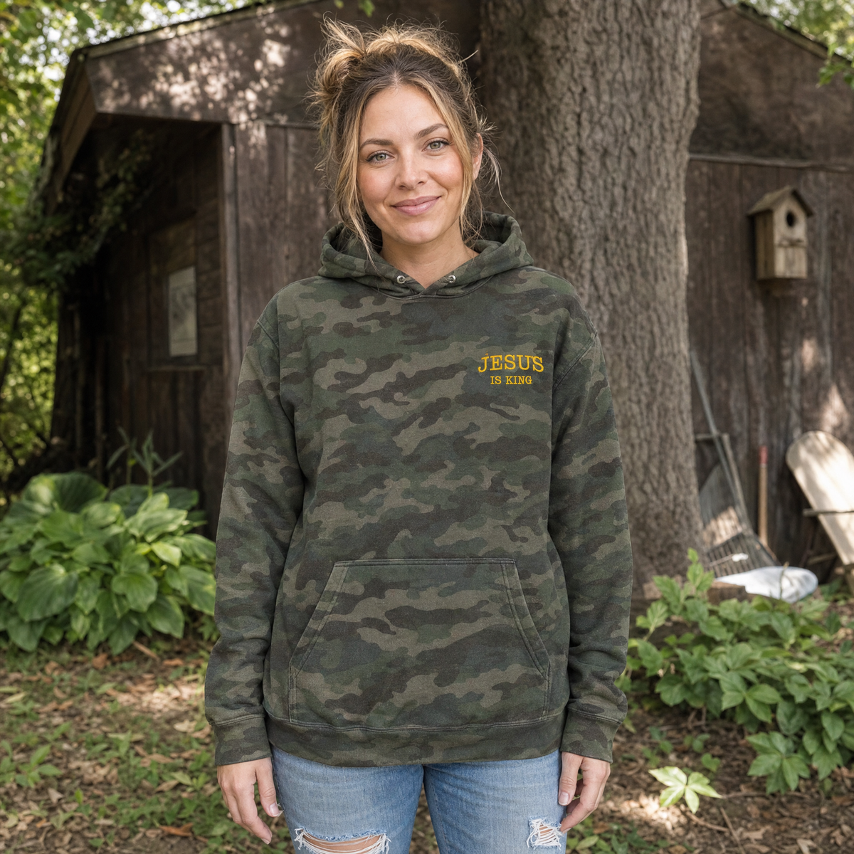 Model wearing the Jesus Is King heavyweight hoodie in Forest Camo, lifestyle image 1