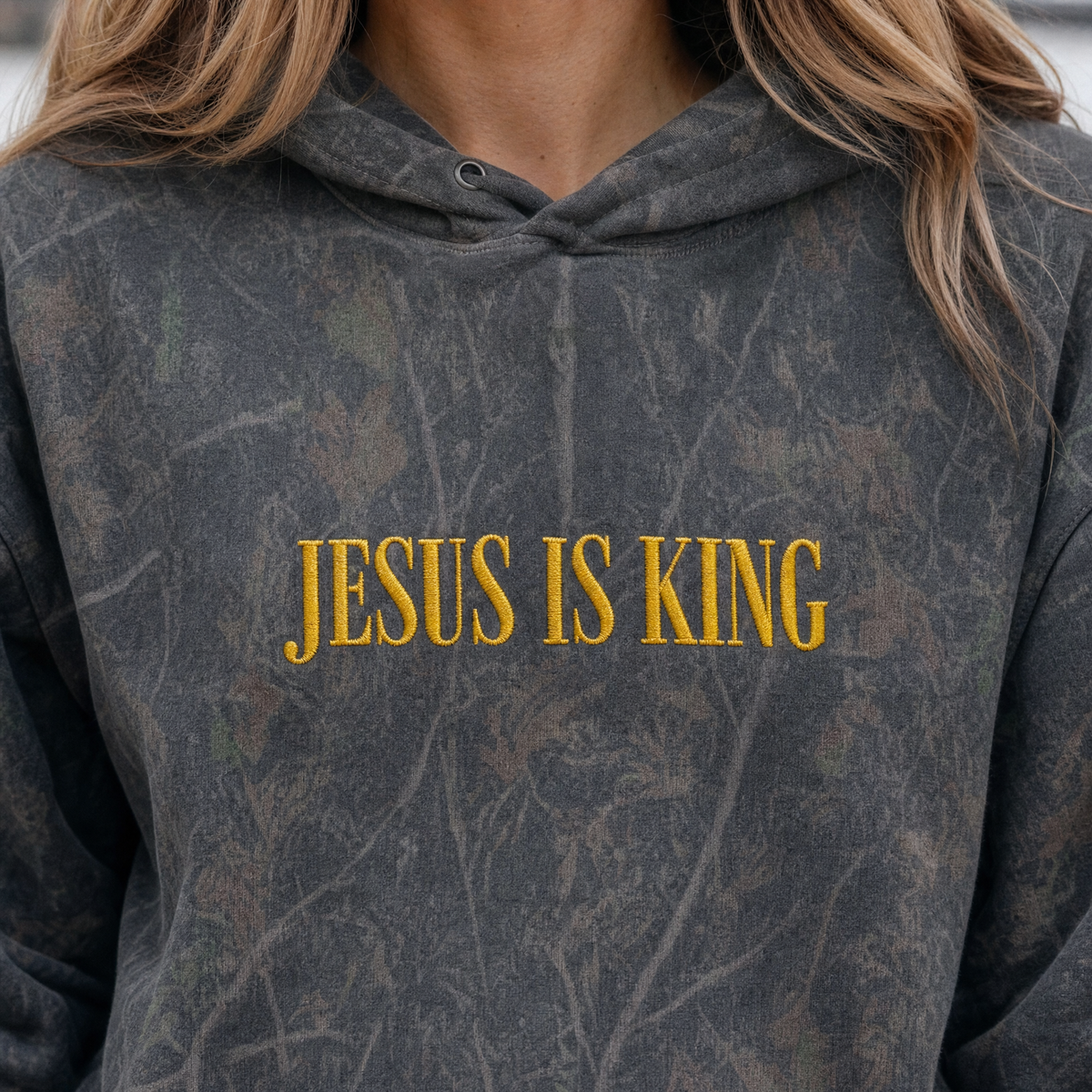 Model wearing the Jesus Is King heavyweight hoodie in Dark Tree Camo, lifestyle image 1