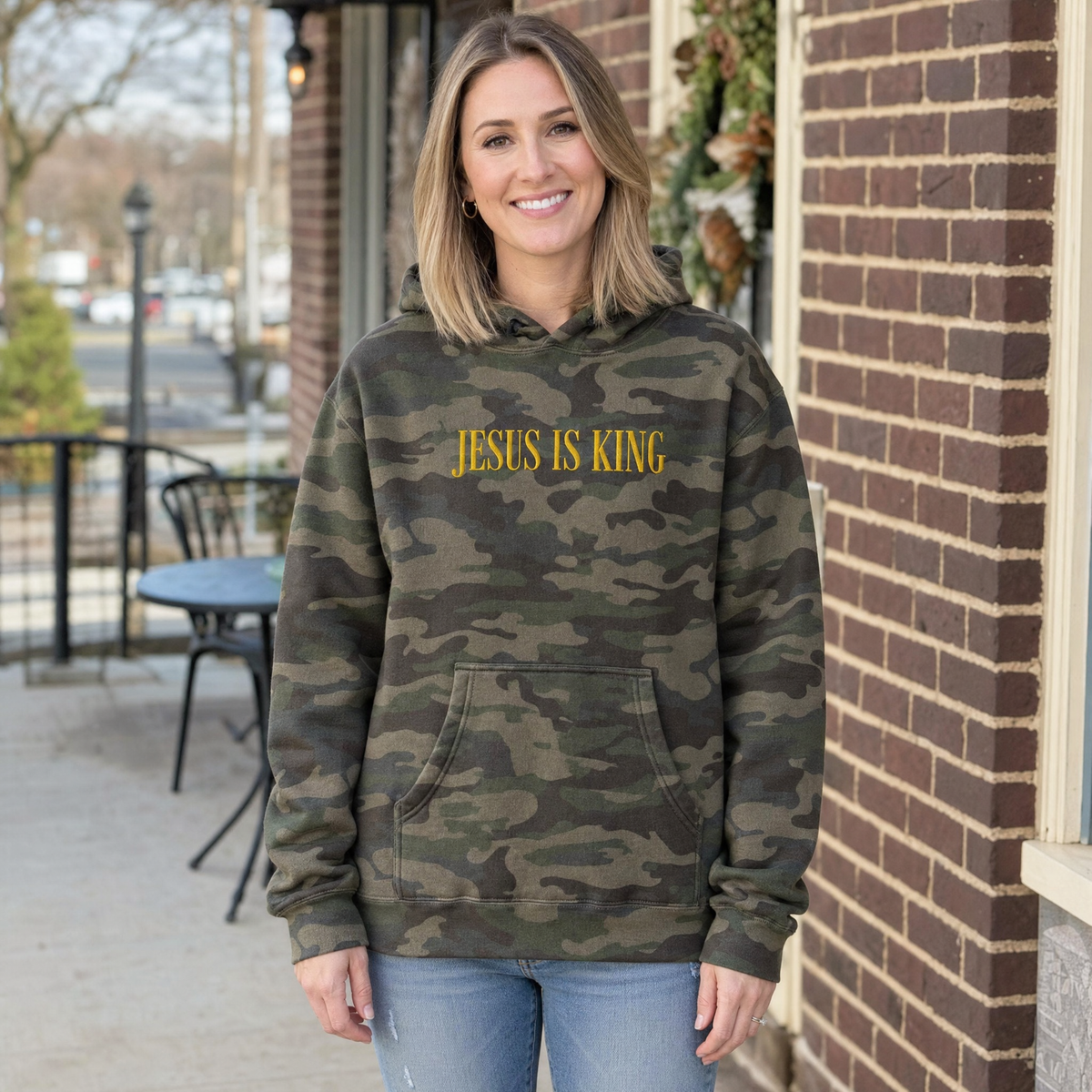 Model wearing the Jesus Is King heavyweight hoodie in Green Camo, lifestyle image 1