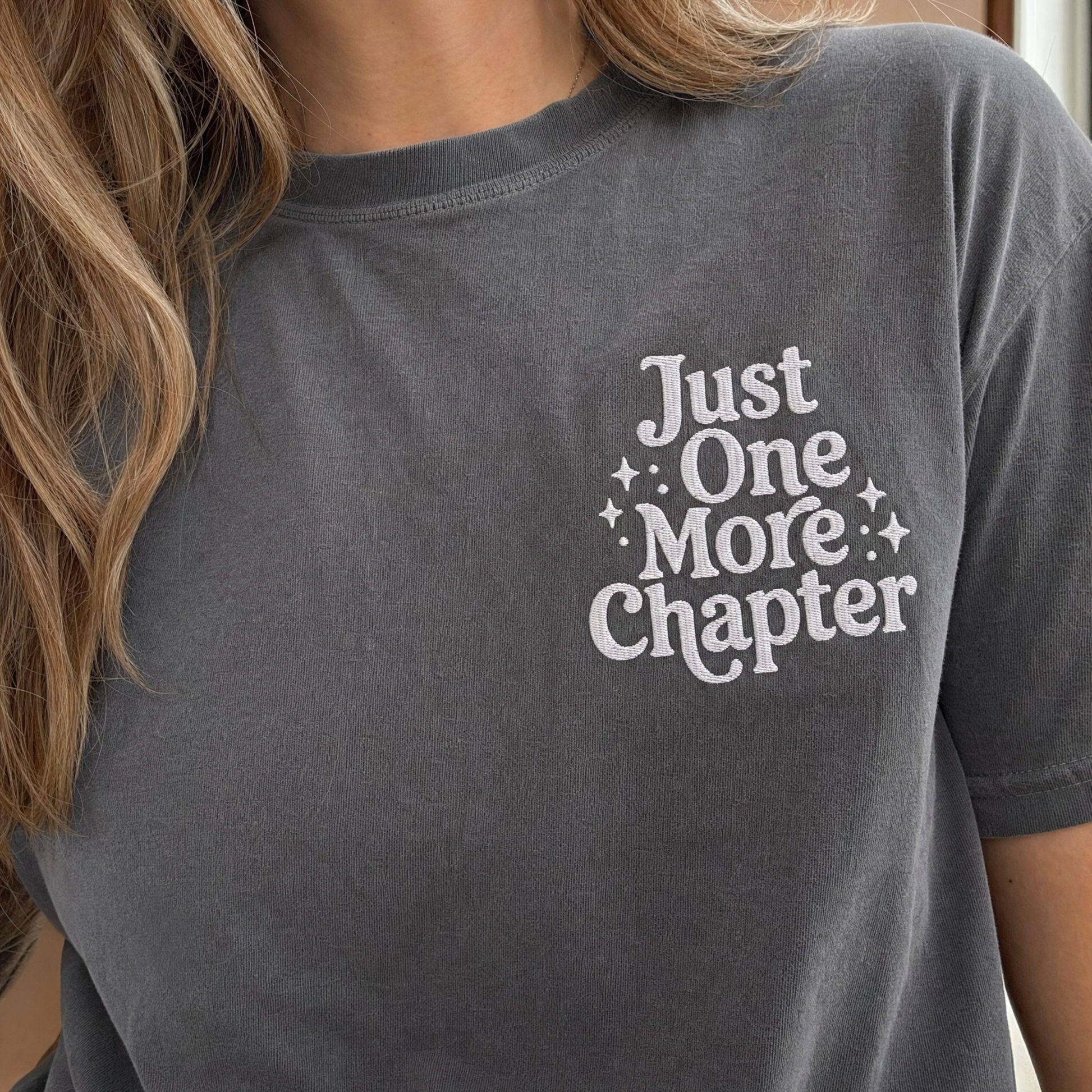 Model wearing the Just One More Chapter comfort colors tee in Pepper, lifestyle image 1