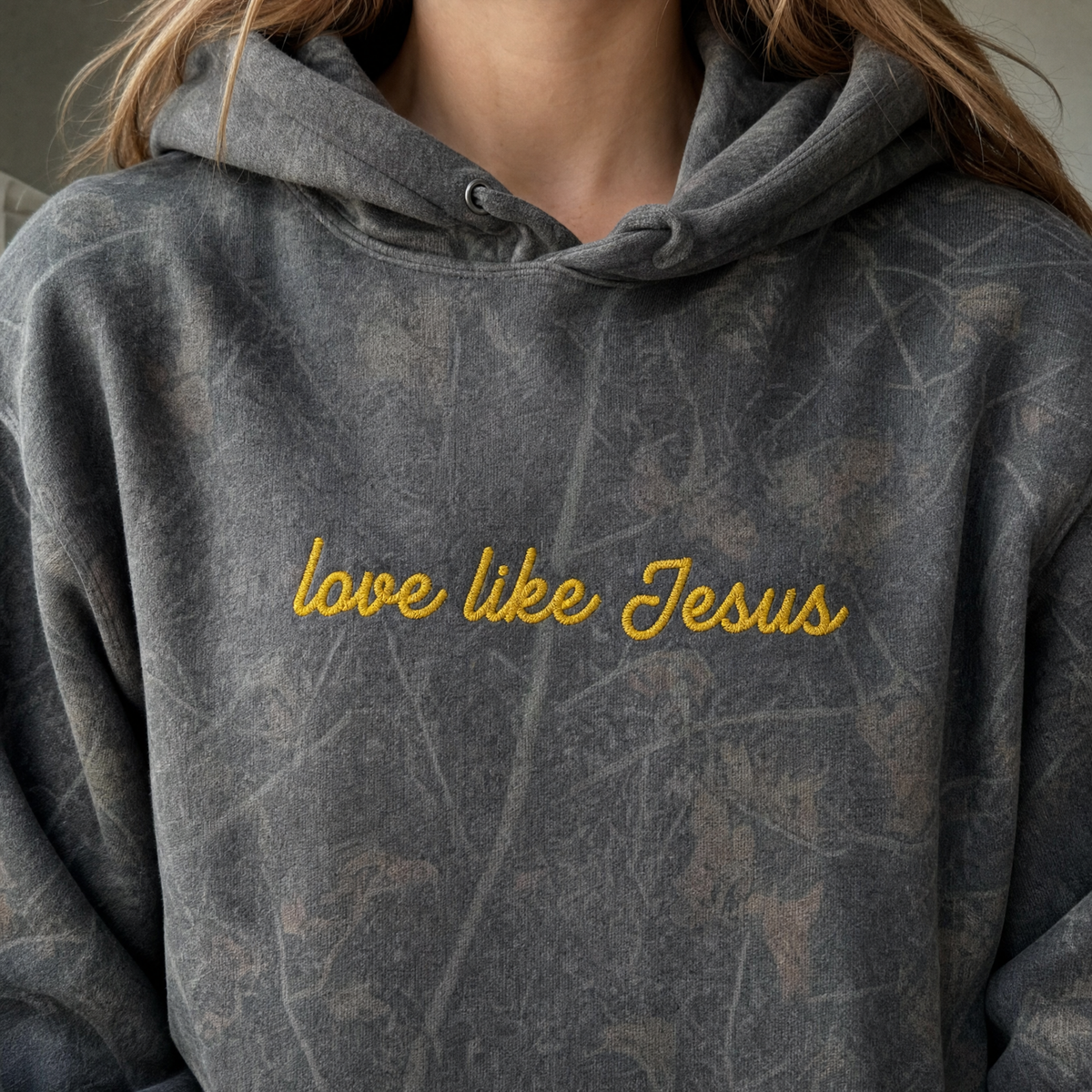 Model wearing the Love Like Jesus heavyweight hoodie in Dark Tree Camo, lifestyle image 1