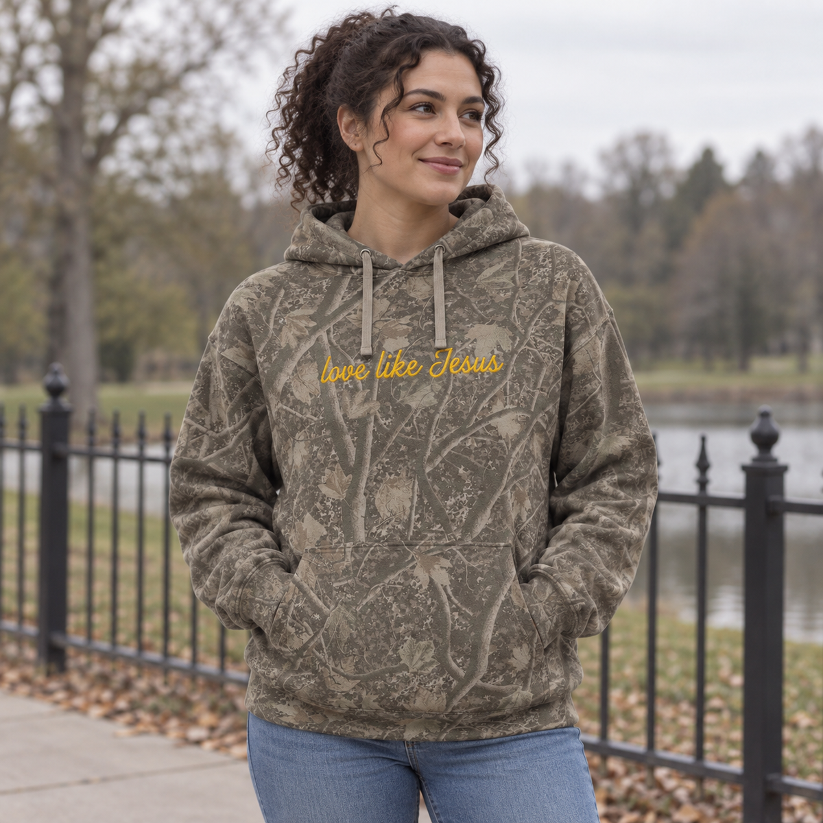 Model wearing the Love Like Jesus heavyweight hoodie in Light Tree Camo, lifestyle image 1