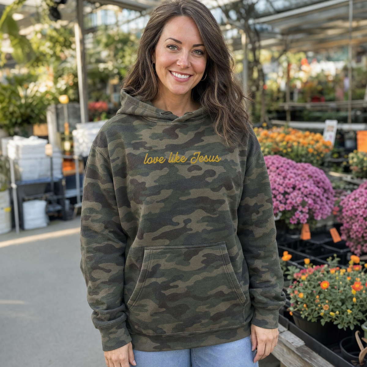 Model wearing the Love Like Jesus heavyweight hoodie in Green Camo, lifestyle image 1