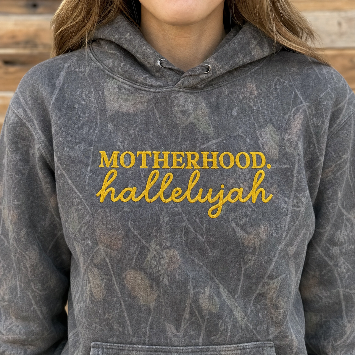 Model wearing the Motherhood Hallelujah heavyweight hoodie in Dark Tree Camo, lifestyle image 1