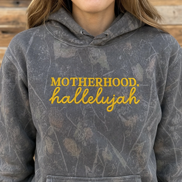 Model wearing the Motherhood Hallelujah heavyweight hoodie in Dark Tree Camo, lifestyle image 1