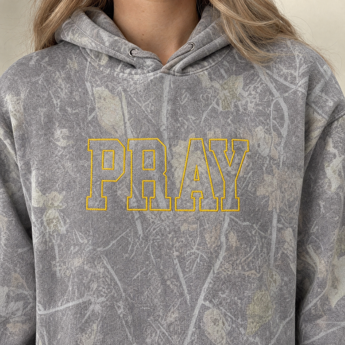 Model wearing the Pray Outline Text heavyweight hoodie in Light Tree Camo, lifestyle image 2