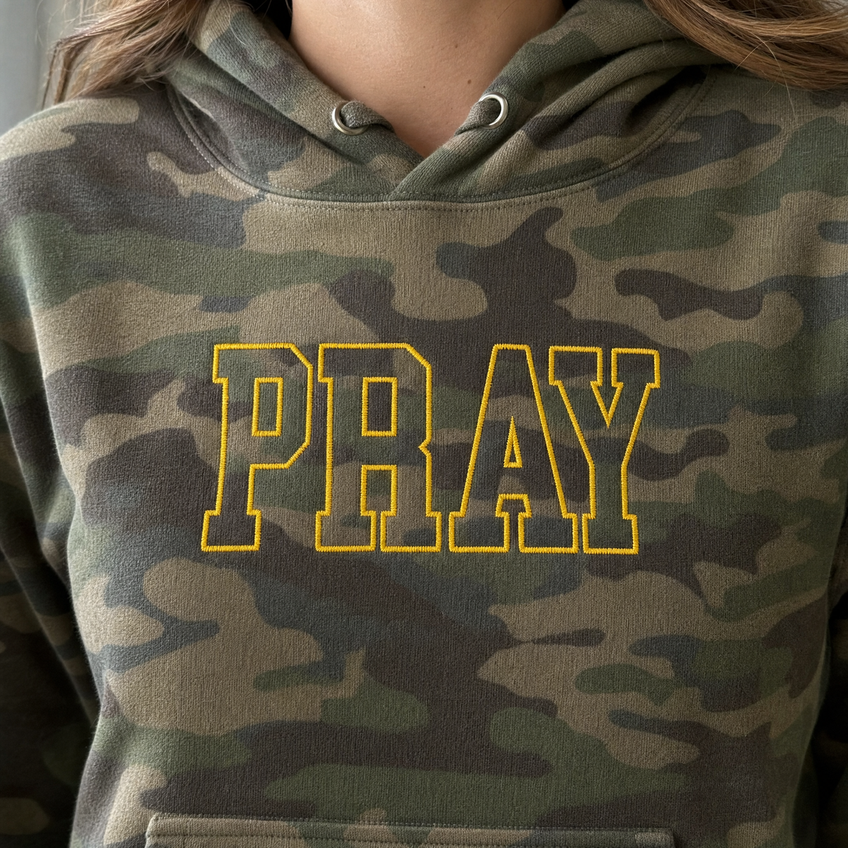 Model wearing the Pray Outline Text heavyweight hoodie in Green Camo, lifestyle image 2