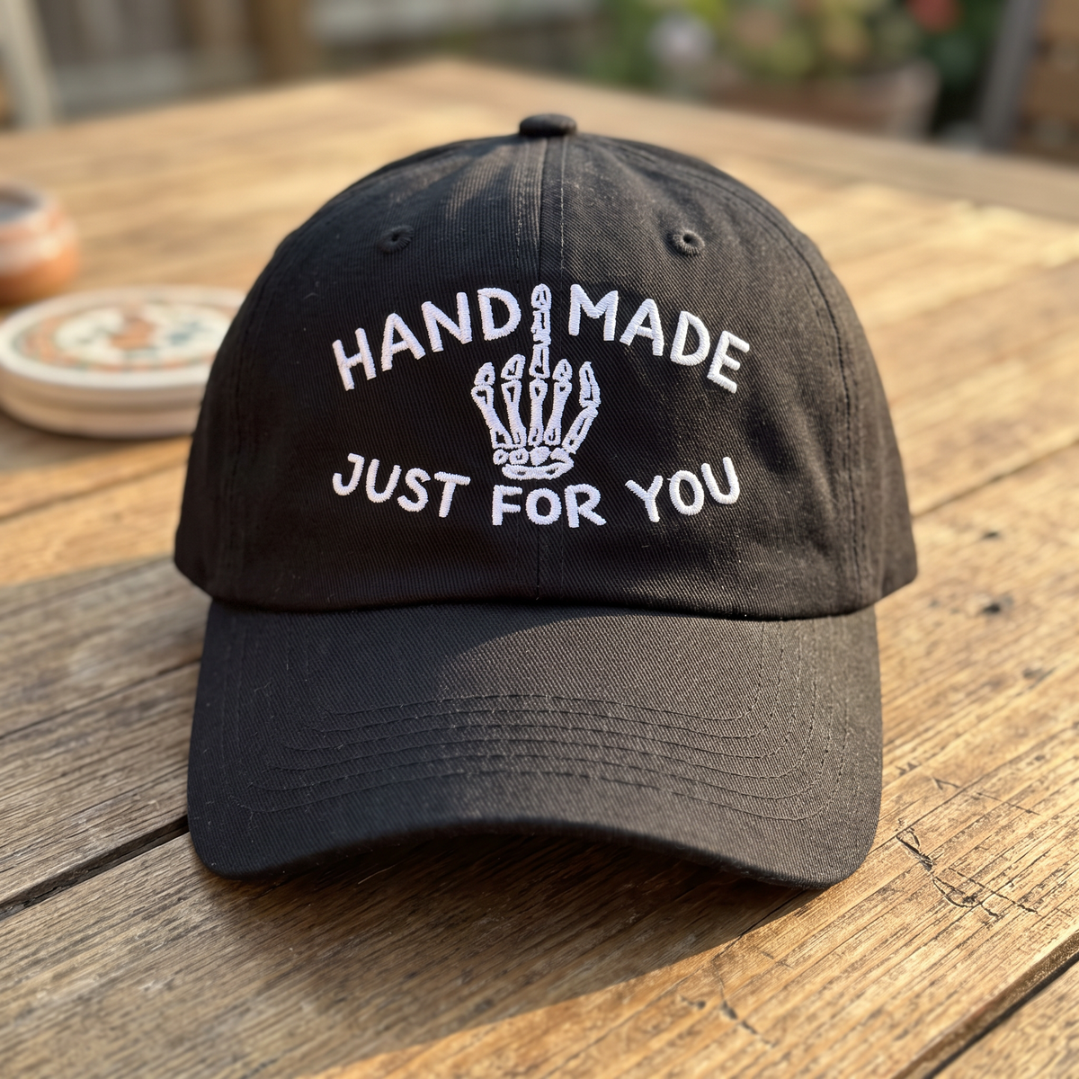 Skeleton Middle Finger embroidered hat in Black resting on a flat surface, lifestyle image 2