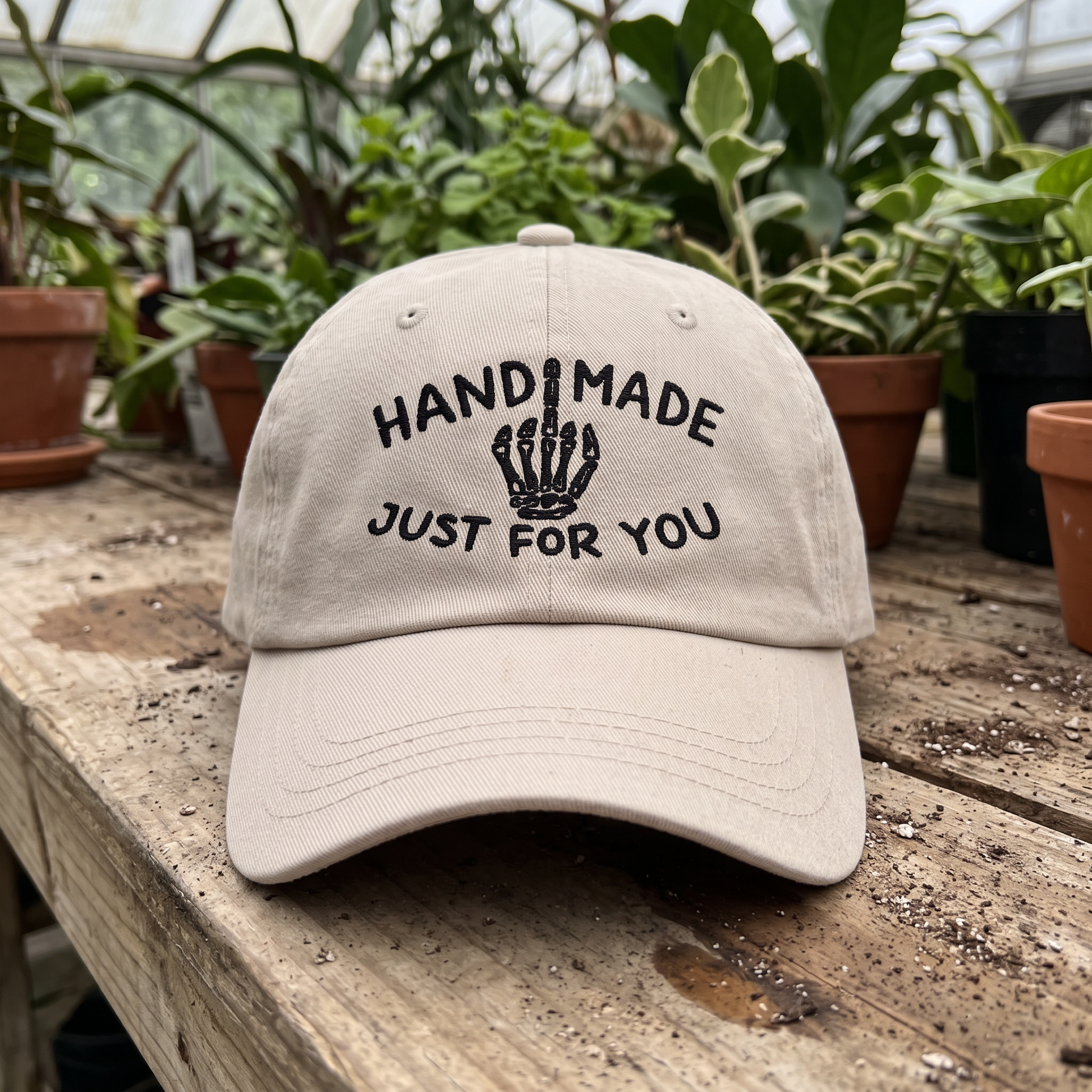 Skeleton Middle Finger embroidered hat in Stone resting on a flat surface, lifestyle image 1