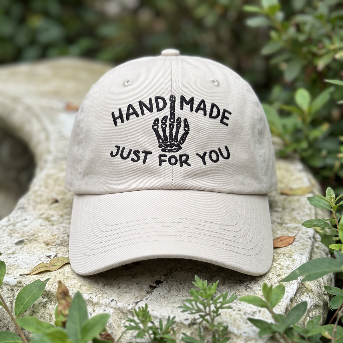 Skeleton Middle Finger embroidered hat in Stone resting on a flat surface, lifestyle image 2