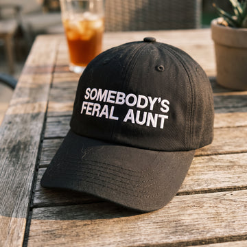 Somebody's Feral Aunt embroidered hat in Black resting on a flat surface, lifestyle image 2