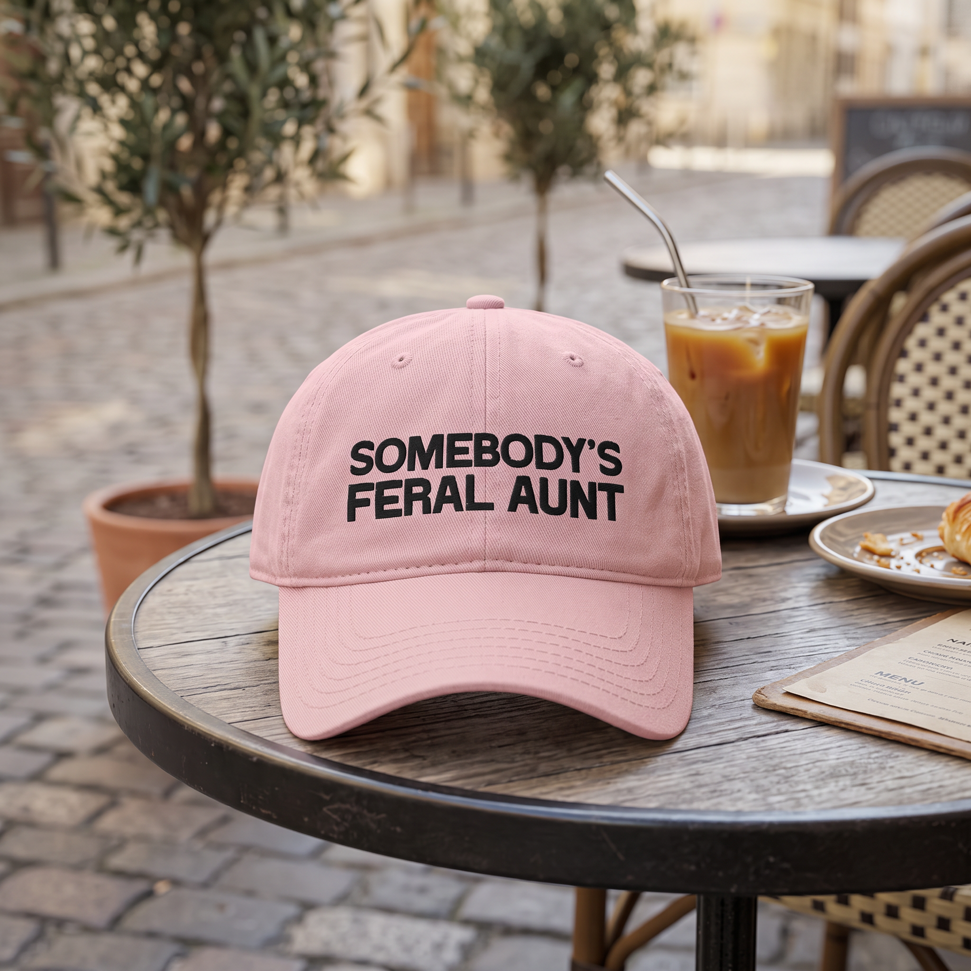 Somebody's Feral Aunt embroidered hat in Dusty Rose resting on a flat surface, lifestyle image 2