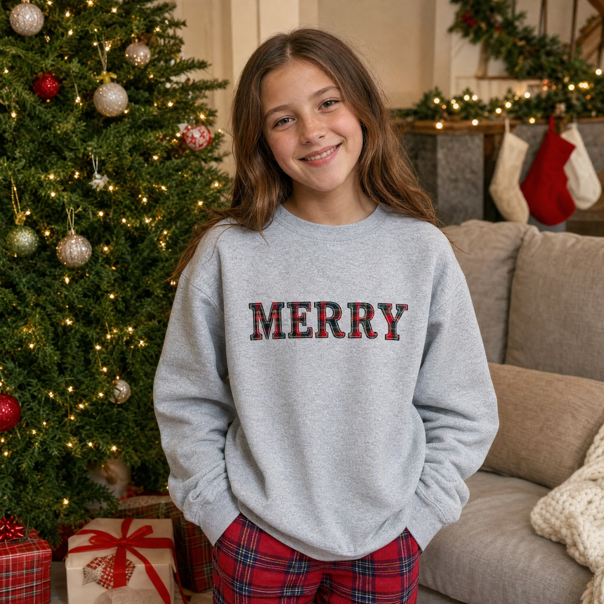 Model wearing the Merry Plaid Text youth sweatshirt in Sport Grey, lifestyle image 1