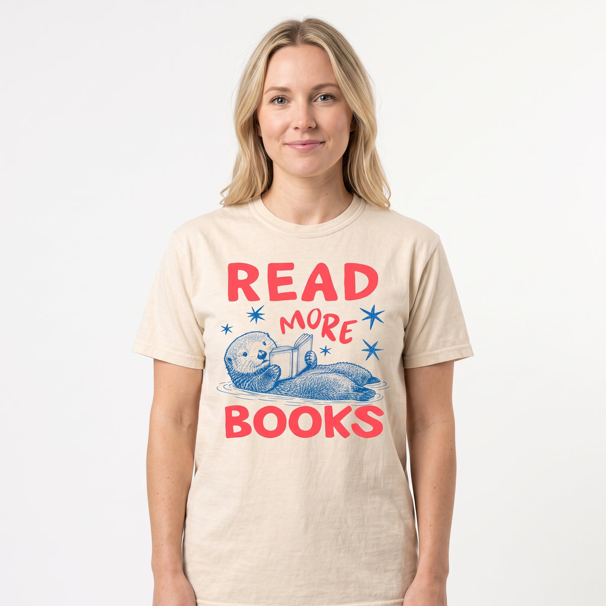 Model wearing the Otter Reading Book comfort colors tee in Ivory, cover image 1
